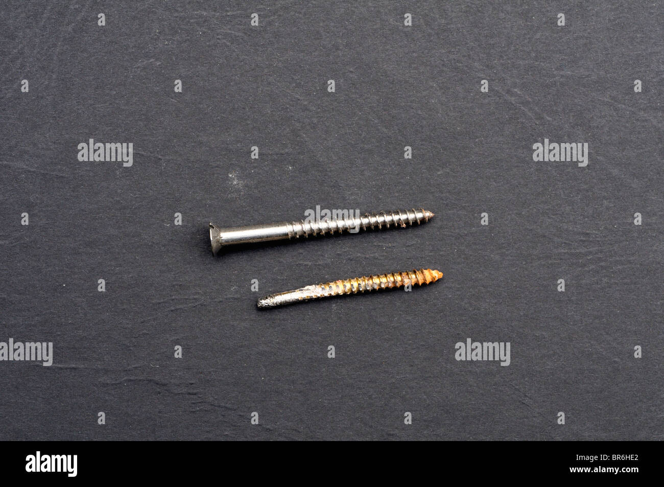 Broken screw compared to an unbroken screw. Stock Photo