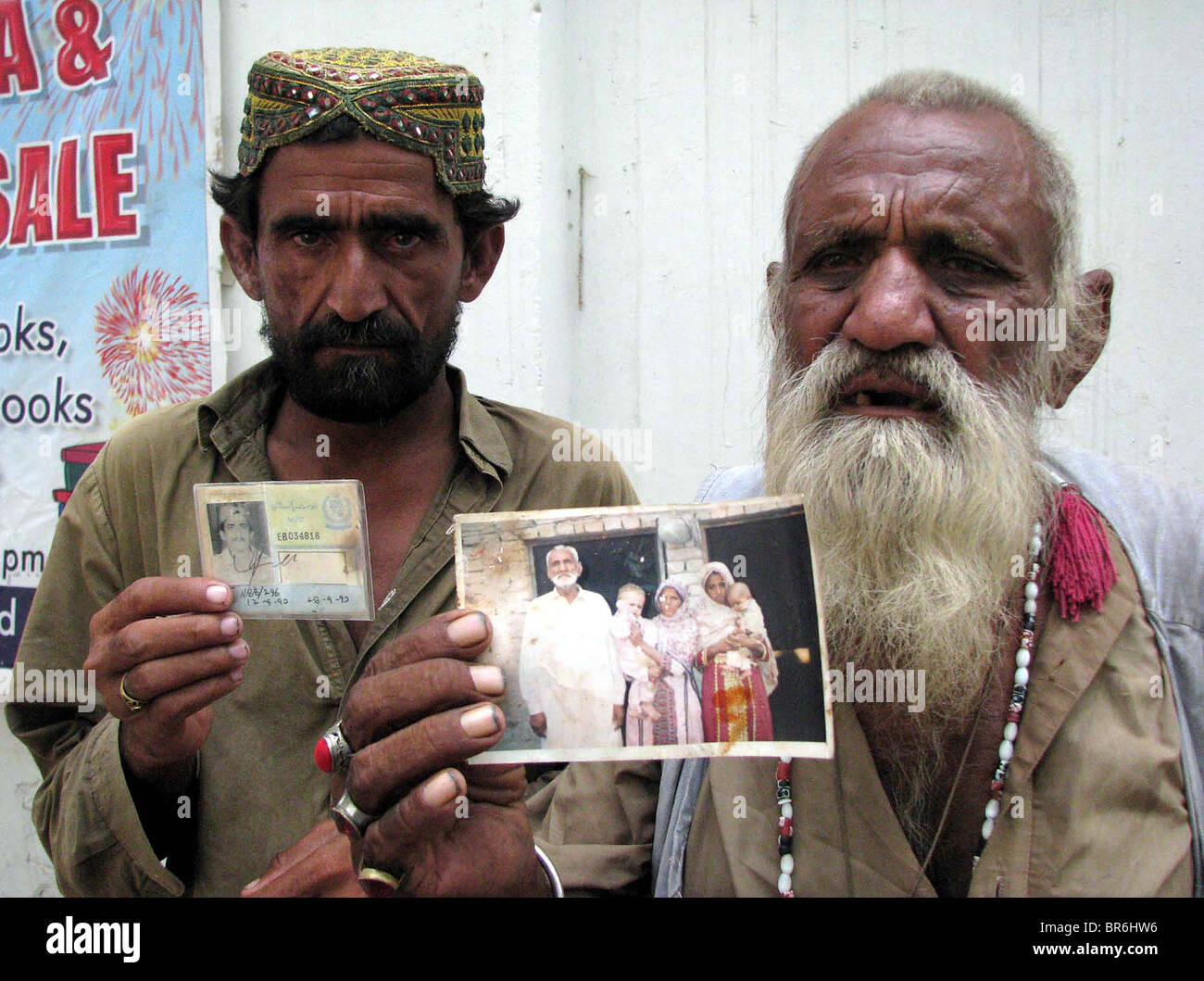 Flood affected men from Jhatpat Goth Dera Murad Jamali hold picture and national identity card of their relatives, who were Stock Photo