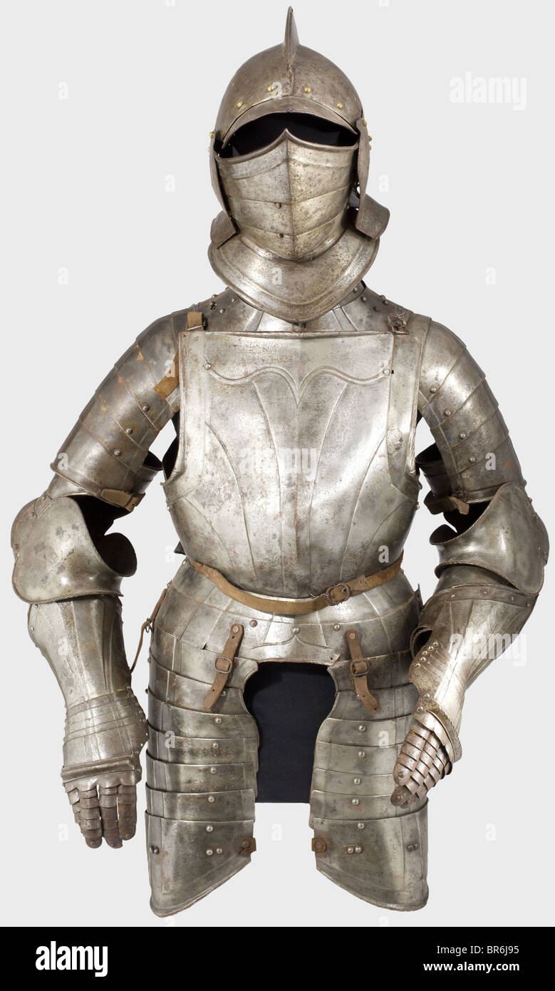 A German suit of armour for a man at arms, circa 1580. Assembled from old pieces. Visor and vambraces are Historismus Period replacements. Burgonet with a two-piece skull and high comb with rolled edge, riveted visor and neck guard, and attached cheek pieces with perforations. Surrounded by brass lining rivets. Three-piece, laminated closeable visor. Hinged bevor with a two-piece gorget and a massive turned under and corded flange. Pauldrons of six lames attached. Full cannons of the vambrace with closed couters. Slightly different fingered gauntlets, missing t, Stock Photo
