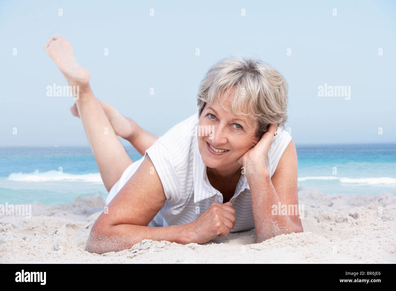 Senior Woman Relaxing On Sandy Beach Stock Photo - Alamy