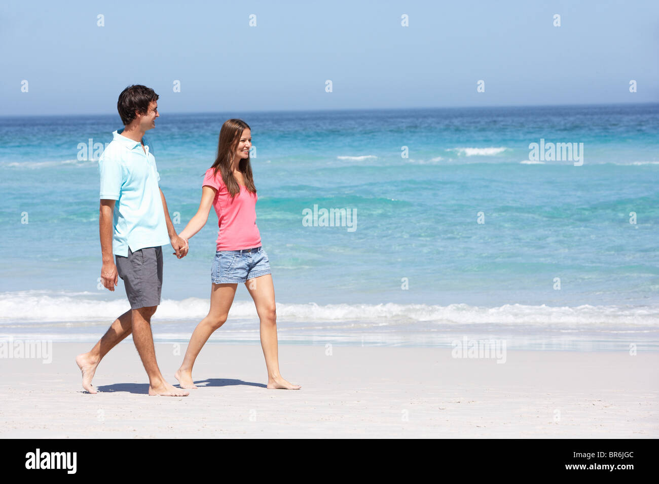 Couple On Holiday Walking Along Sandy Beach Stock Photo - Alamy