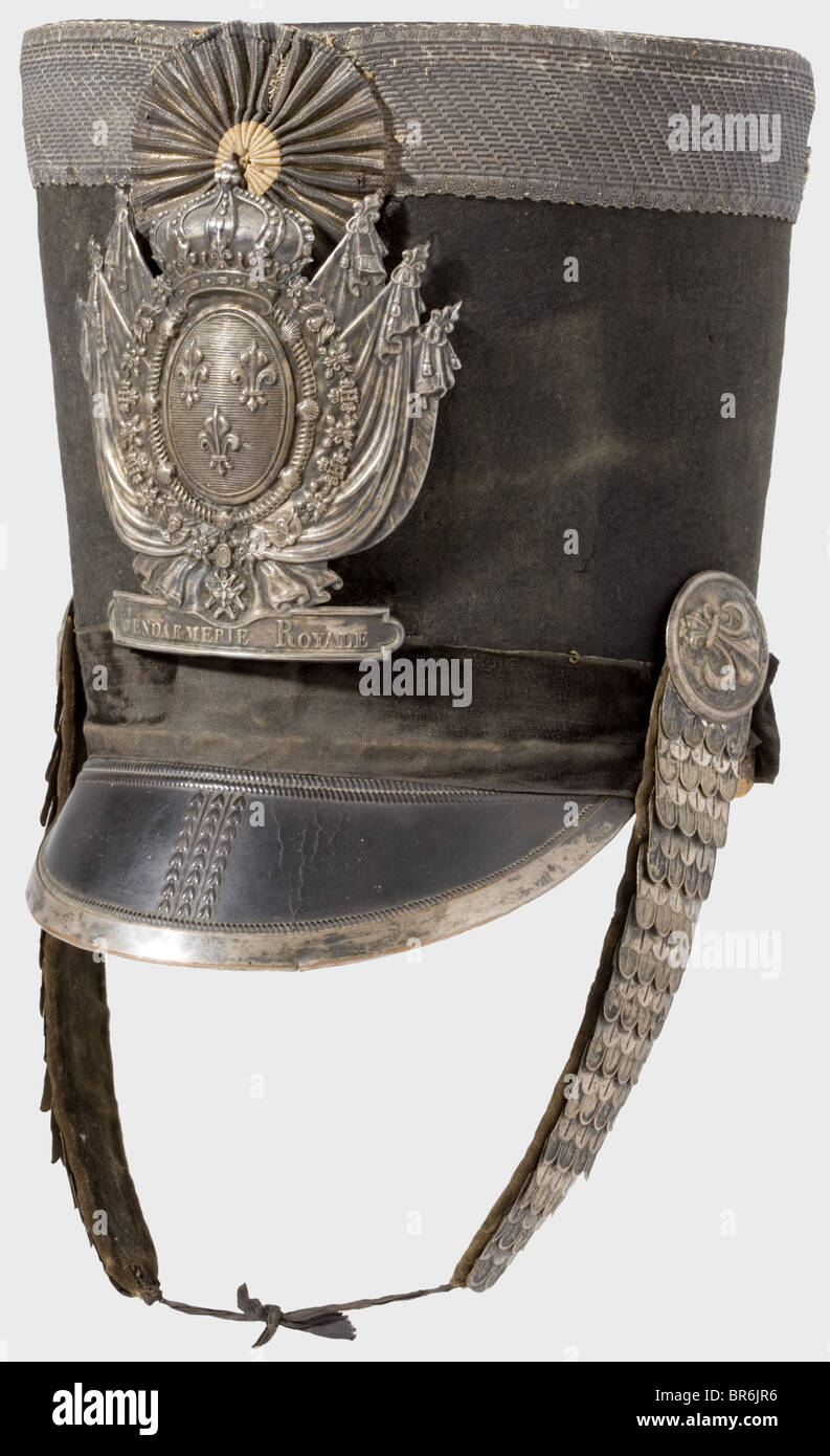 A shako for officers of the Gendarmerie Royale., Black felt body, stamped leather peak with a silver rail on the edge. Black velvet band (damaged). Leather crown edged with 40 mm wide silver lace. Silver fleur-de-lys emblem bearing the inscription, 'Gendarmerie Royale'. Silver metal chinscales. Silver lace cockade. Lining complete. Height 25 cm. Silver lace is heavily darkened. During the period 1815 to 1830, the Gendarmerie Royale consisted only of the Departements Corse and Seine. Very rare headgear. historic, historical, 19th century, French Restauration, Fr, Stock Photo