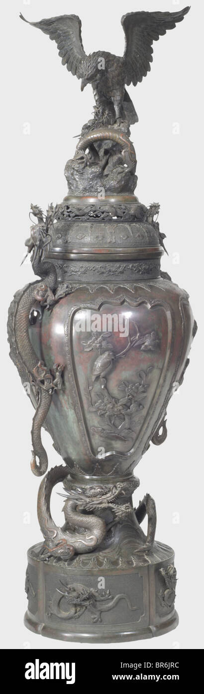 A Japanese floor vase, 19th century. Patinated bronze cast in several pieces. Three-dimensionally worked lid displaying a Phoenix and a dragon. Ornamented bellied corpus sectioned into four fields bearing plants and birds in relief. Inserted handles shaped as dragons on each side (one leg of a dragon broken but included). Tall, detachable base in relief with surrounding depictions of dragons with fully plastic heads (one head included but loose, one fixed with screws). Another three-dimensional dragon winds itself between corpus and base. Small defects, repairs, Stock Photo