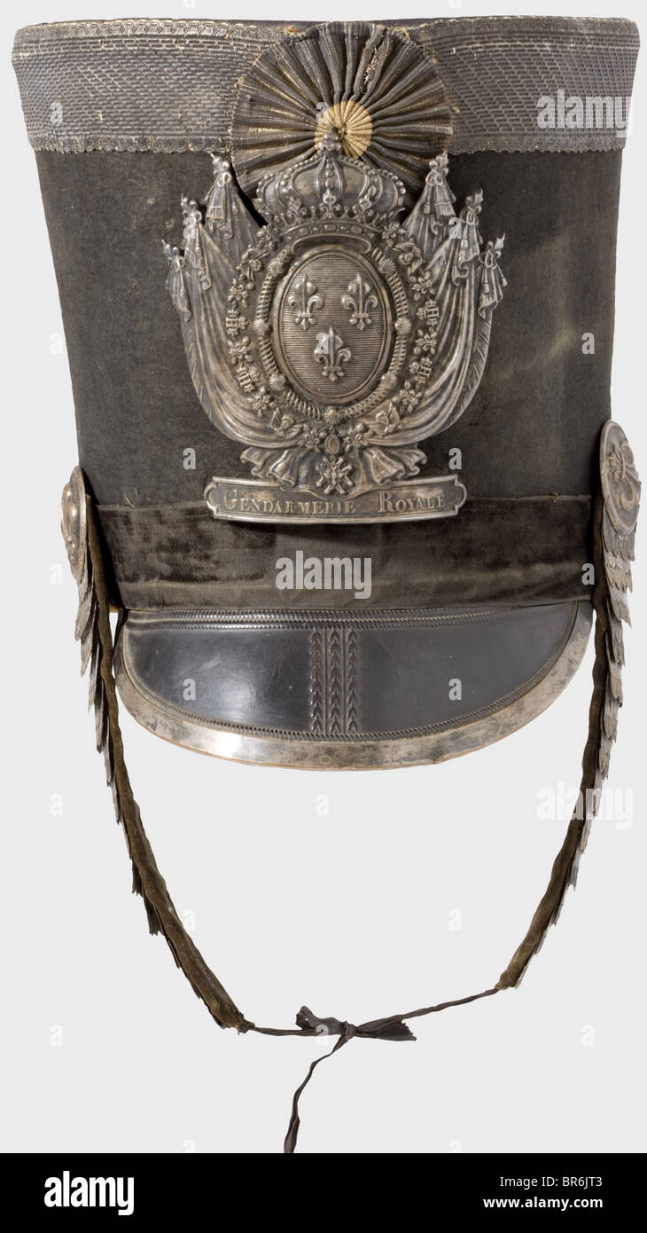 A shako for officers of the Gendarmerie Royale., Black felt body, stamped leather peak with a silver rail on the edge. Black velvet band (damaged). Leather crown edged with 40 mm wide silver lace. Silver fleur-de-lys emblem bearing the inscription, 'Gendarmerie Royale'. Silver metal chinscales. Silver lace cockade. Lining complete. Height 25 cm. Silver lace is heavily darkened. During the period 1815 to 1830, the Gendarmerie Royale consisted only of the Departements Corse and Seine. Very rare headgear. historic, historical, 19th century, French Restauration, Fr, Stock Photo