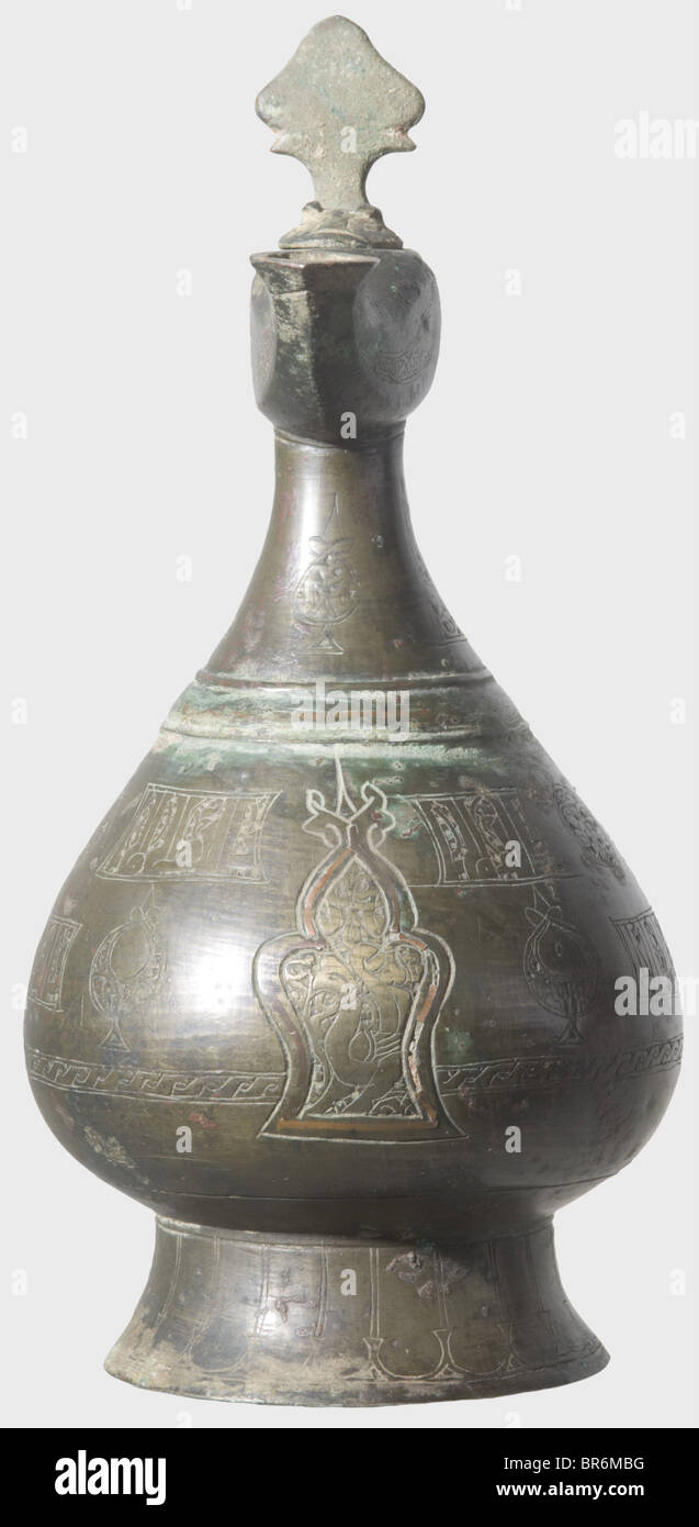 An engraved, pitcher-shaped bronze oil lamp, Khorasan circa 1200. Drop-shaped body with conical foot, lateral handle and engraved cartouches along the periphery bearing ornaments and inscriptions, respectively. The front with the image of a mythical creature surrounded by a palmette-shaped copper frame. On the neck a small oil lamp with hinged lid. Brown-green patina. Height 24 cm. historic, historical, 13th century, Ottoman Empire, object, objects, stills, clipping, clippings, cut out, cut-out, cut-outs, Stock Photo