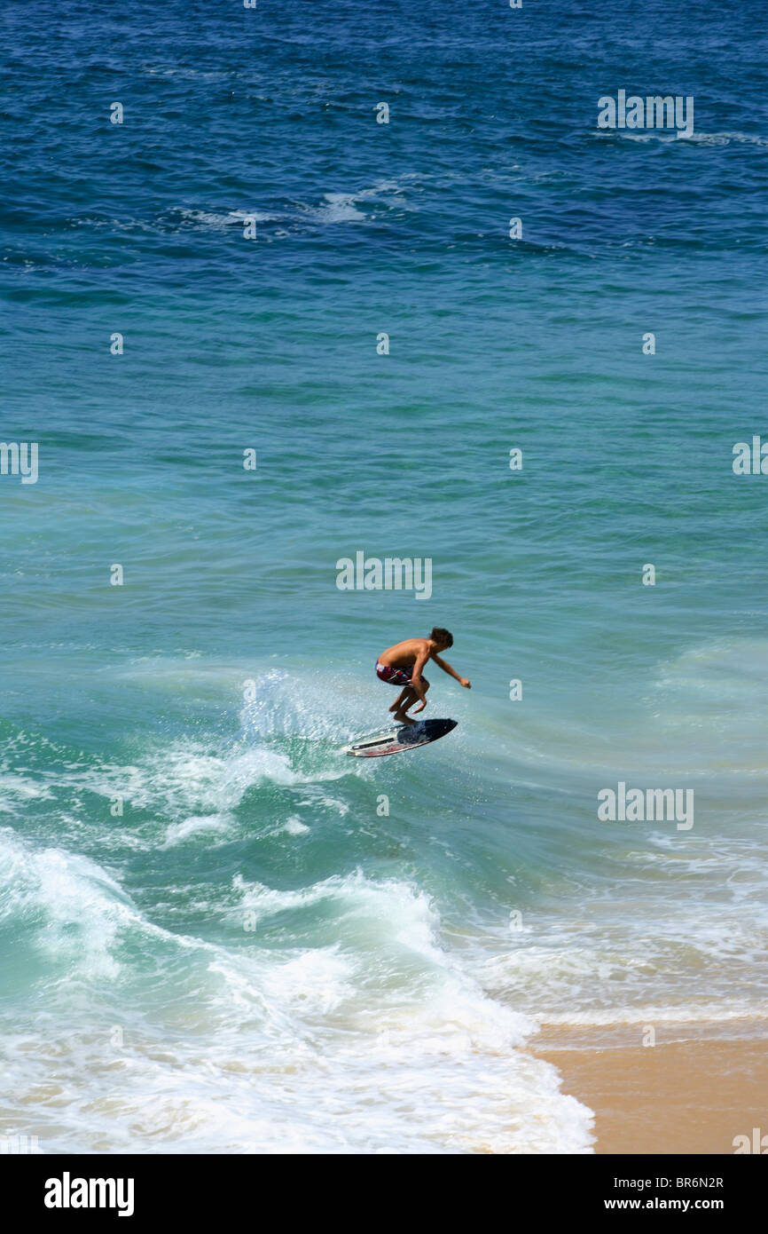Skimboarder plays in the surf at Divorce Beach near El Arco in Cabo San Lucas in Baja Mexico. Stock Photo