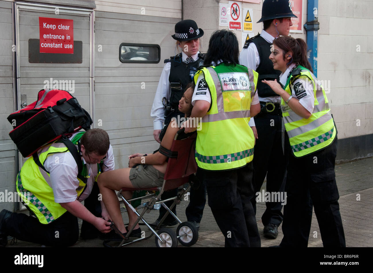 Police and St john's ambulance paramedics treating woman Notting Hill Carnival Stock Photo