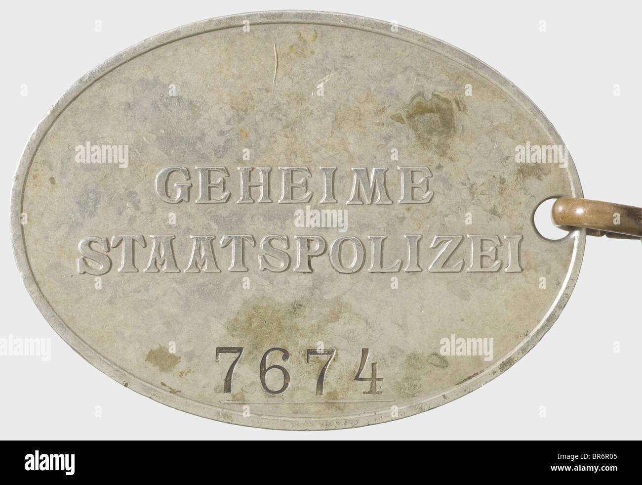 A badge '7674' of the GESTAPO., Nickel-silver, raised national eagle and the inscription 'GEHEIME STAATSPOLIZEI' (Secret State Police) in the typical caption, above the stamped number '7674'. Dimensions 37 x 51 mm. On a non-ferrous metal chain with snap hook and buttonhole toggle, also remnants of gilding. In addition an expertise of authenticity by Don Bible, September 2008. Of utmost rareness. historic, historical, 1930s, 1930s, 20th century, object, objects, stills, clipping, clippings, cut out, cut-out, cut-outs, insignia, symbols, symbol, emblem, emblems, Stock Photo