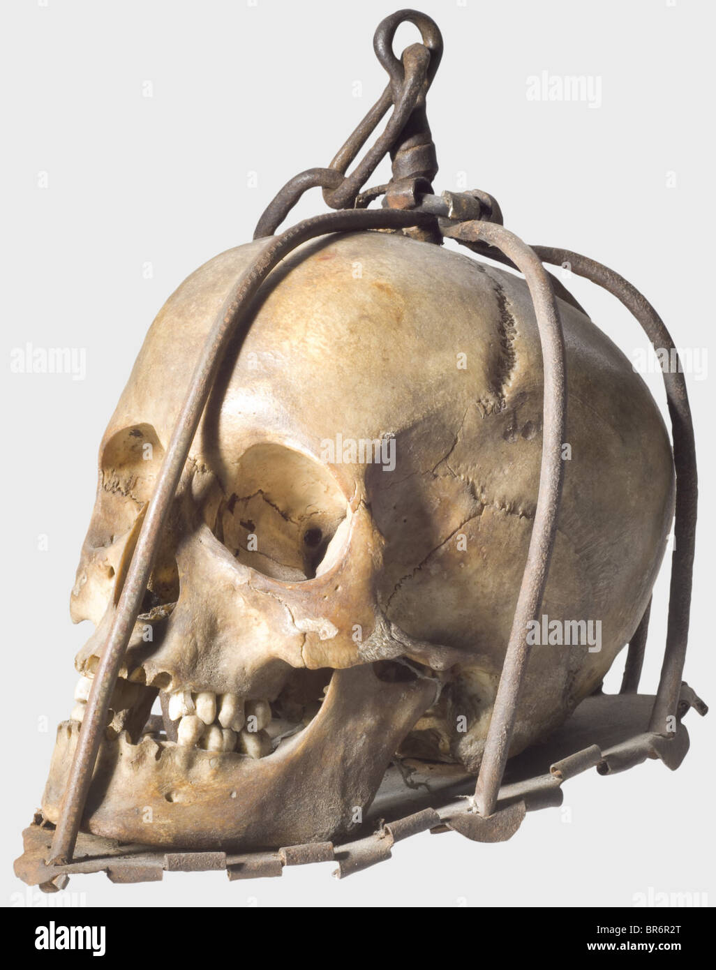 A skull of an execution victim, Germany, 16th/17th century. Wrought iron cage consisting of six bars (one replaced), cotter-pinned to an iron baseplate. The bars joined at the crown with an attached suspension chain. Within the cage a female(?) skull showing clear sign of age. Height 22 cm. Devices like this were hung at execution places to deter delinquents. historic, historical,, people, 17th century, 16th century, instrument of torture, torture device, instruments of torture, torture devices, object, objects, stills, clipping, clippings, cut out, cut-out, cu, Stock Photo