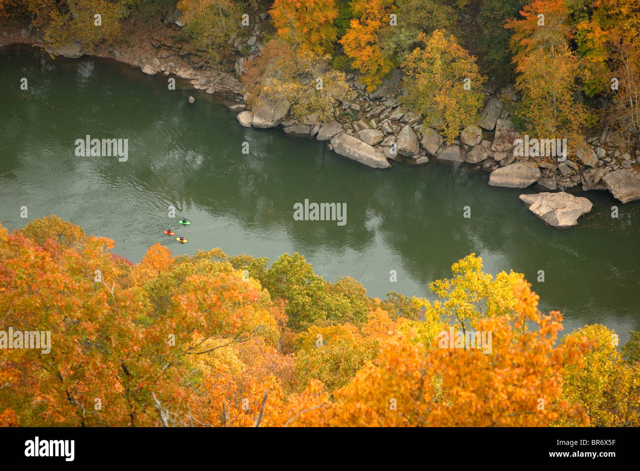 Whitewater kayakers float by fall colors along the New River near Fayettville WV. Stock Photo