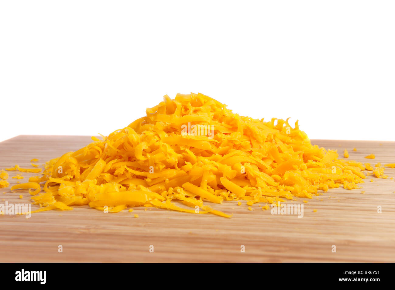 Freshly grated cheese on a cutting board with a white background for use as a design element or copy. Stock Photo