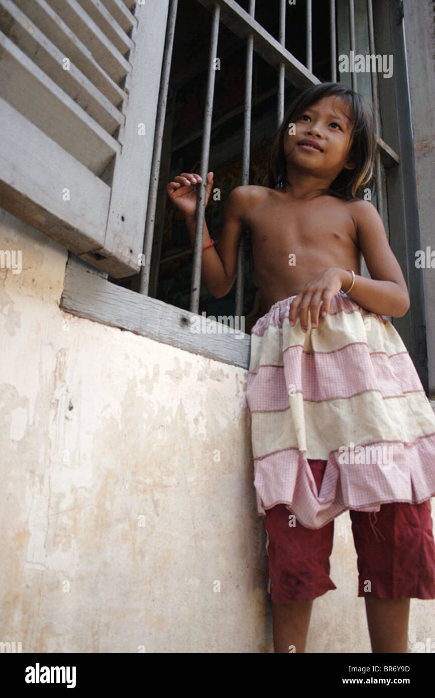 A young girl who lives in a squatter's slum in Phnom Penh, Cambodia, holds  onto the bars of a window at a monk's home Stock Photo - Alamy