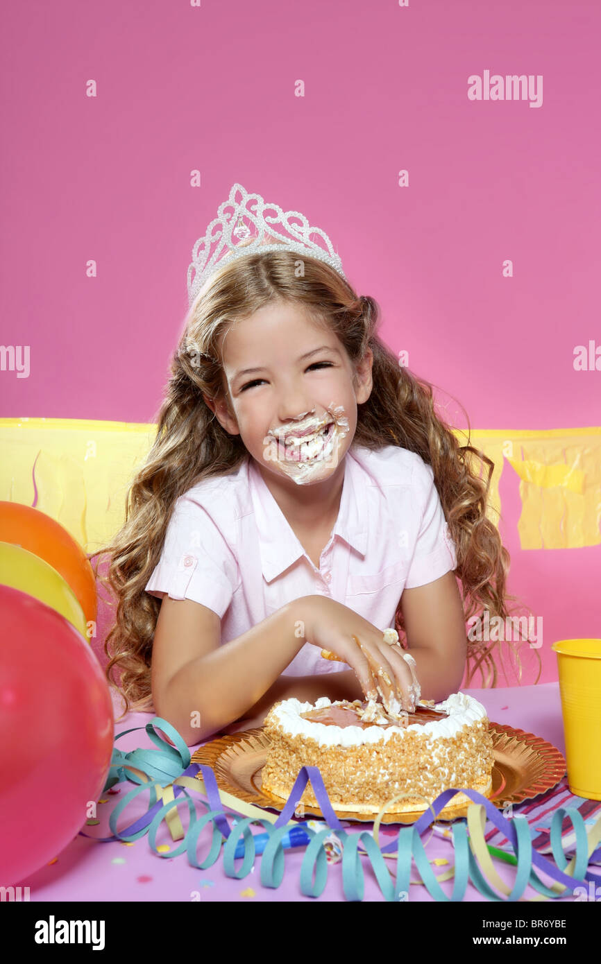 little blond birthday party girl eating cake with hands on pink