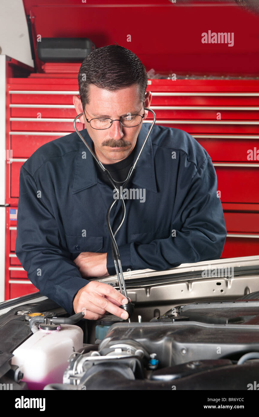 An automobile mechanic examines an engine for unusual sounds using a mechanic's stethoscope. Stock Photo