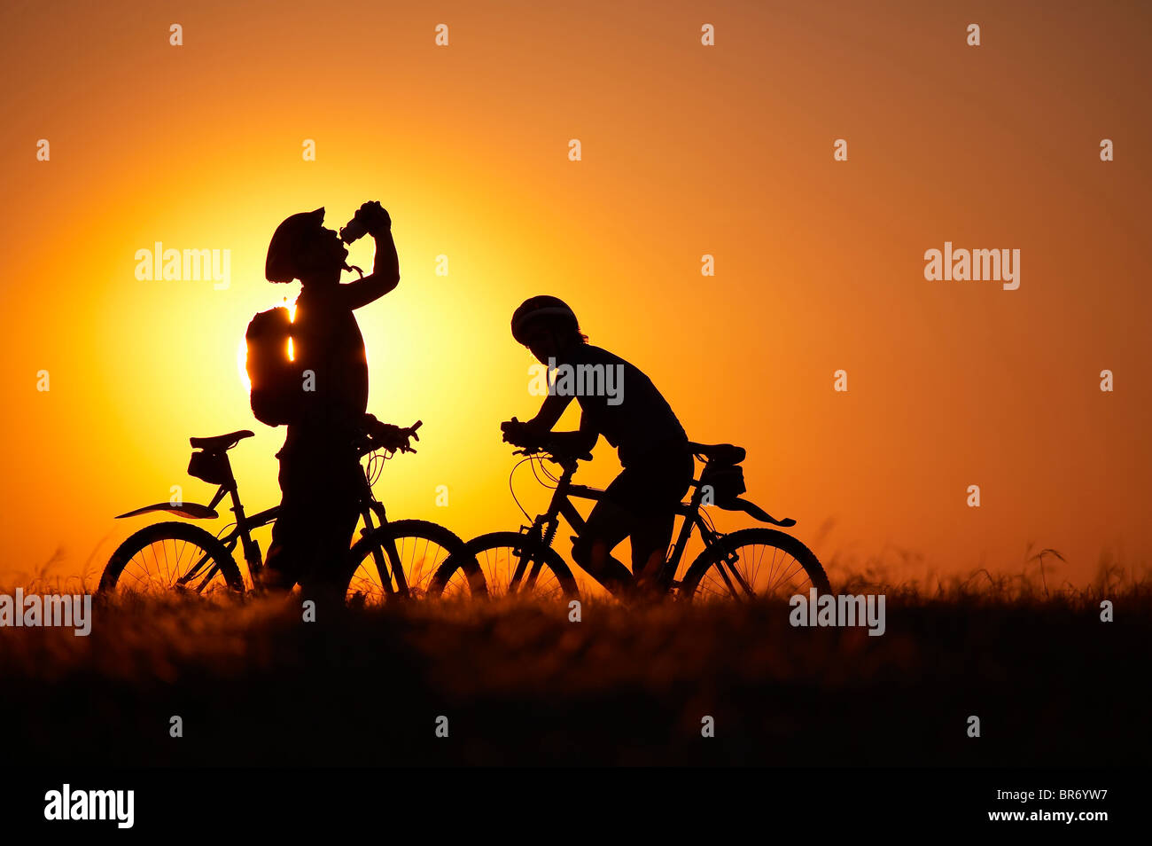 Man taking a drink from a water bottle and woman on mountain bikes