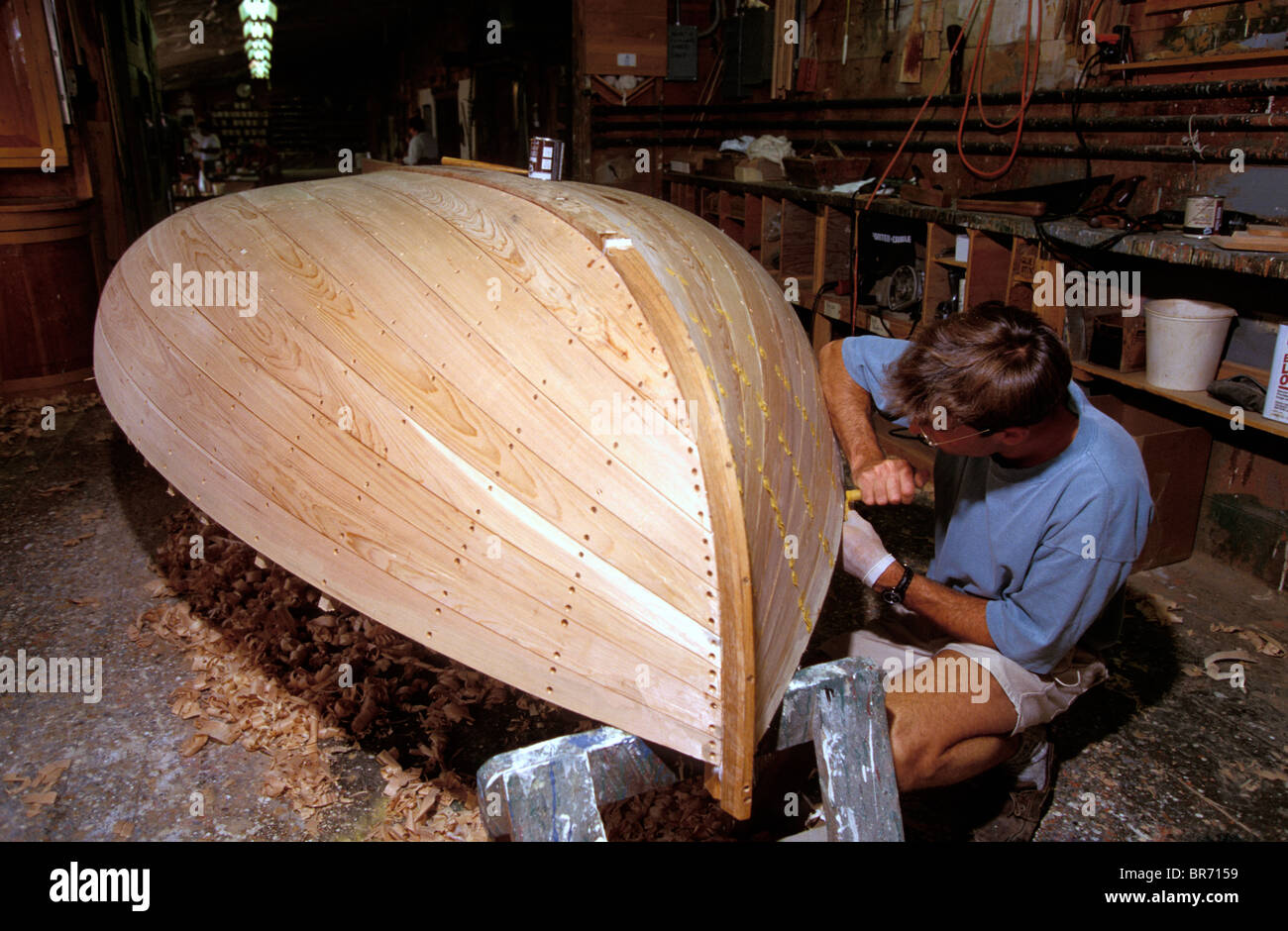 A traditional Beetlecat builder working on the bottom of a new boat at the International Yacht Restoration School in Newport, Rh Stock Photo