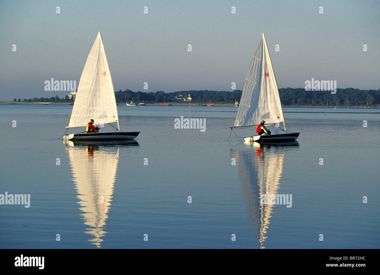 Two people sailing Laser dinghies in the early morning calm, Cape Cod, USA. Stock Photo