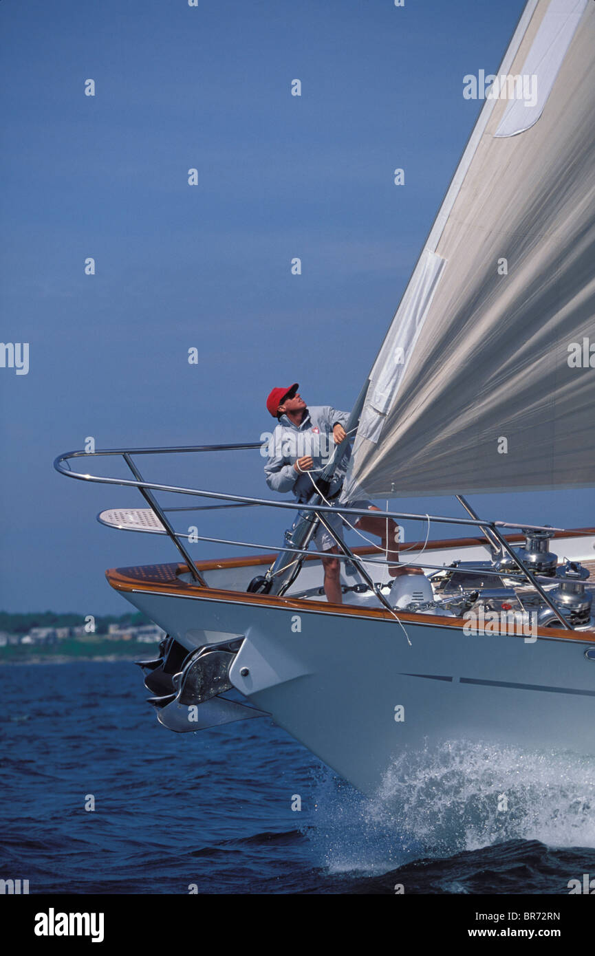 Bowman pulling the luff cord on a big 120ft sloop sailing upwind off Newport Rhode Island, USA Stock Photo