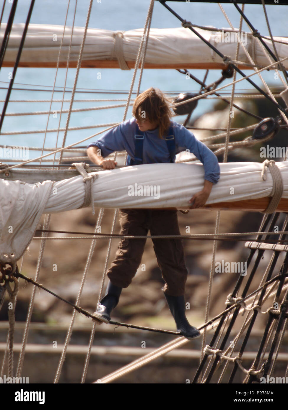 Young man working up the rigging of an old wooden ship, Cornwall, UK Stock Photo