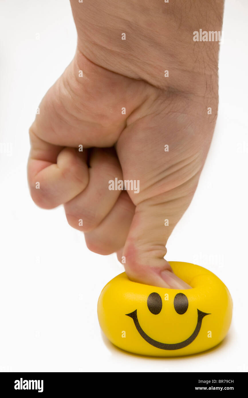 Yellow Happy Face Being Squeezed By A Thumb; Edmonton, Alberta, Canada Stock Photo