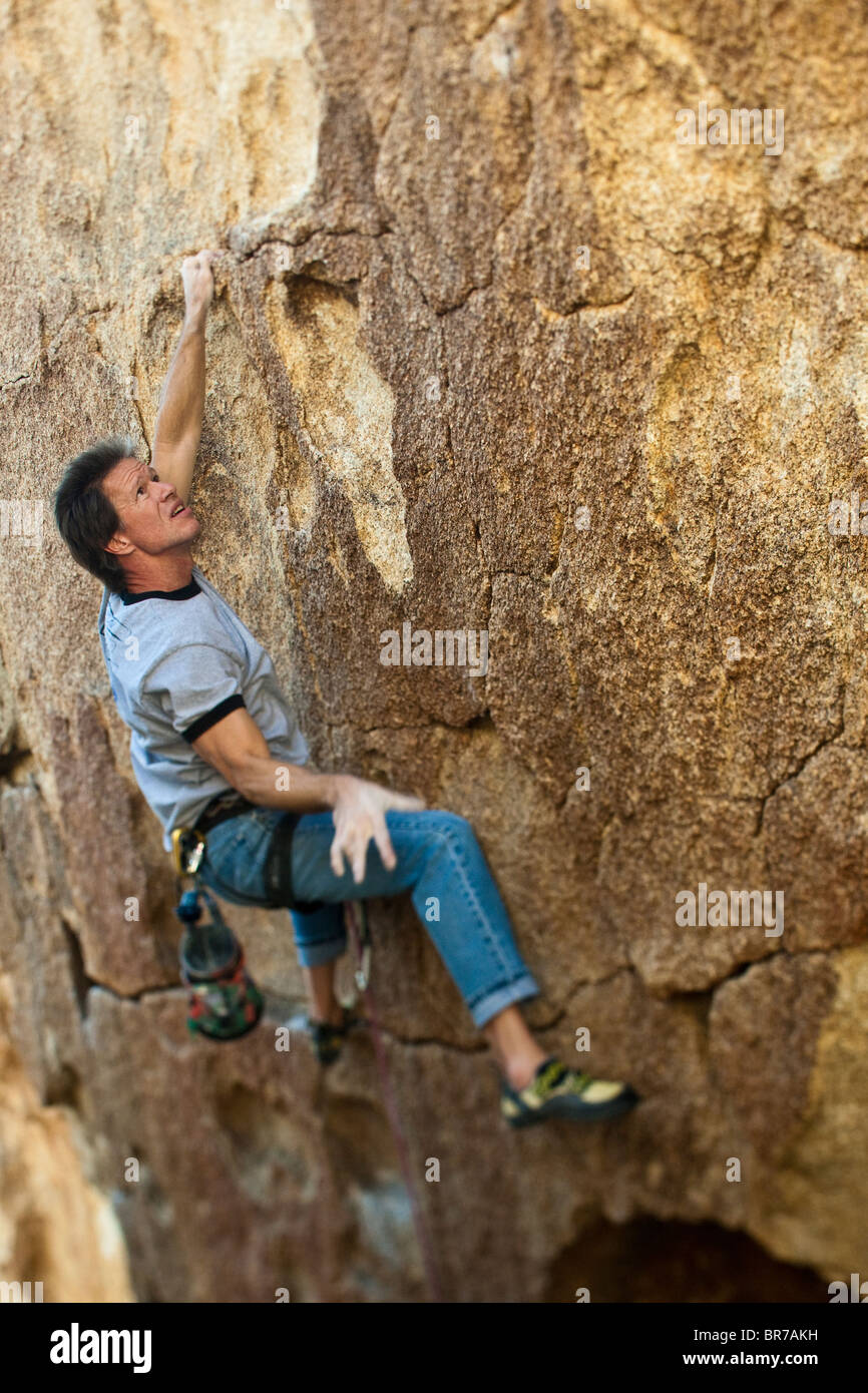 Rock climber grips a crack on a  sheer cliff. Stock Photo