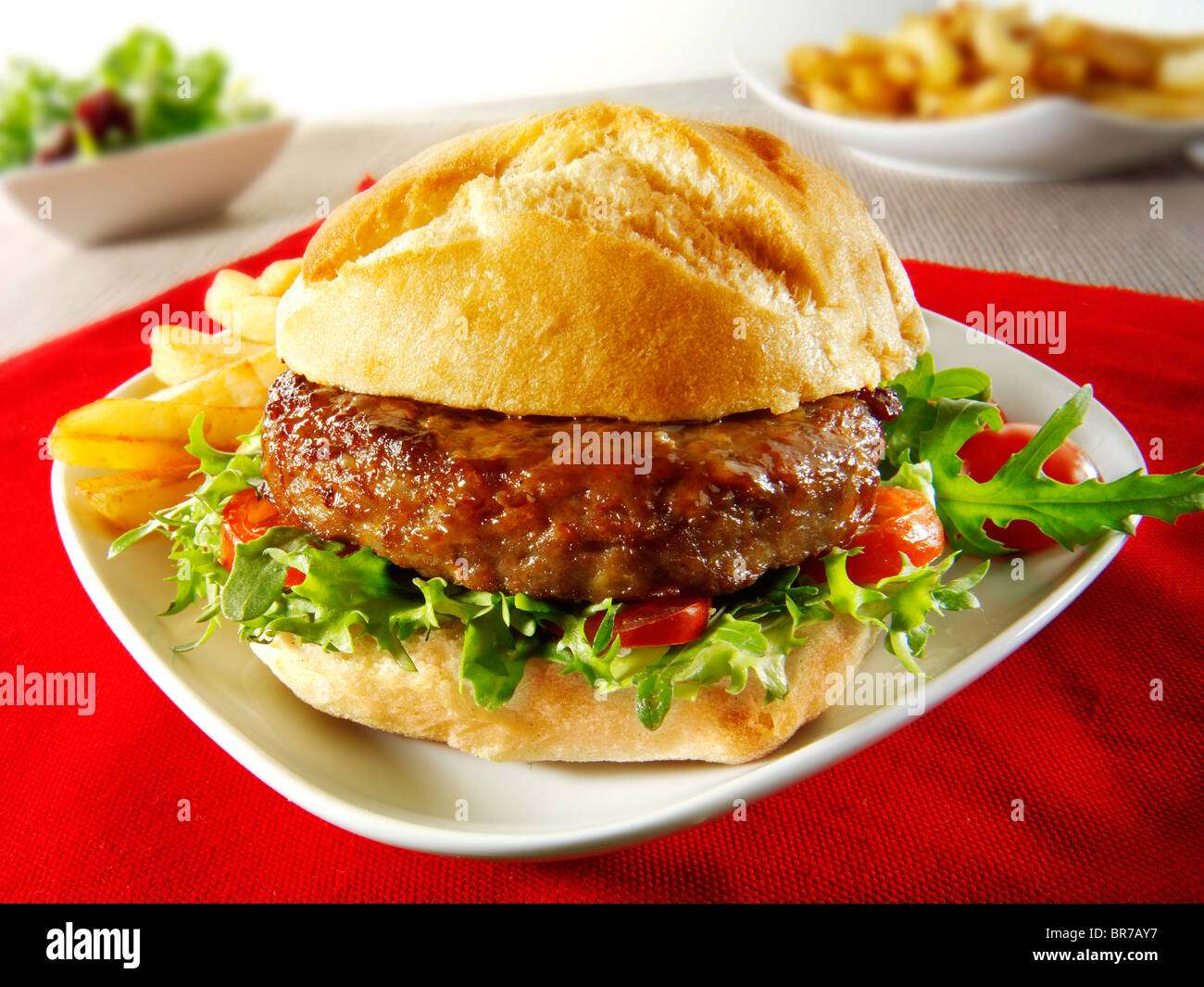 Beef burgers in a bread bun with salad & chips Stock Photo