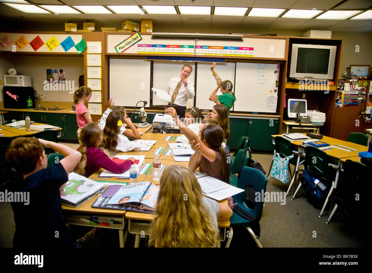 Students' hands go up in answer to a question as a middle school teacher conducts an enthusiastic class in San Clemente, CA. Stock Photo