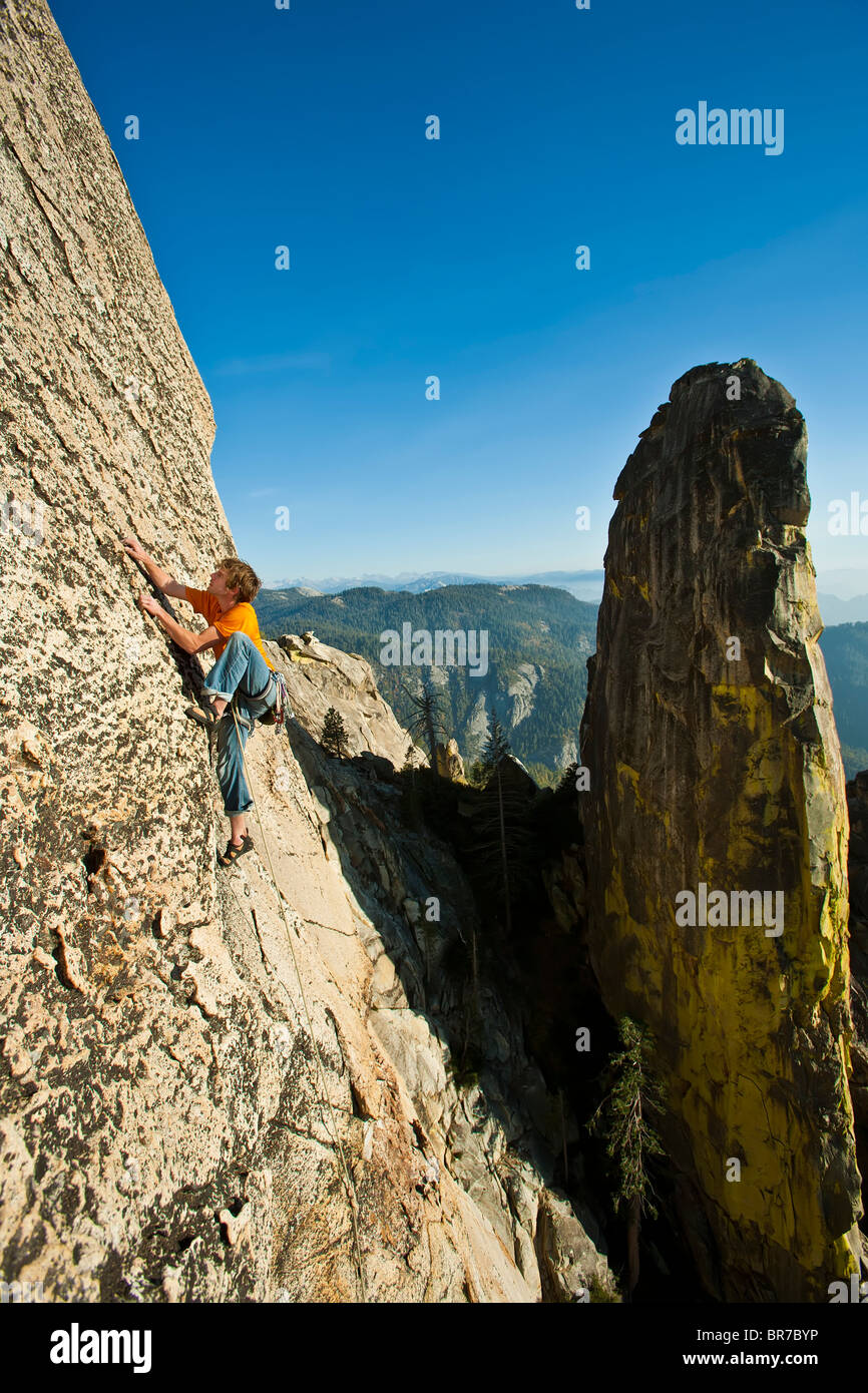 Male climber clings to a steep rock face. Stock Photo