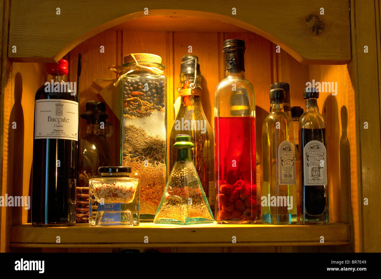 Oils and vinegars bottles with spice jars in a kitchen store cupboard Stock Photo