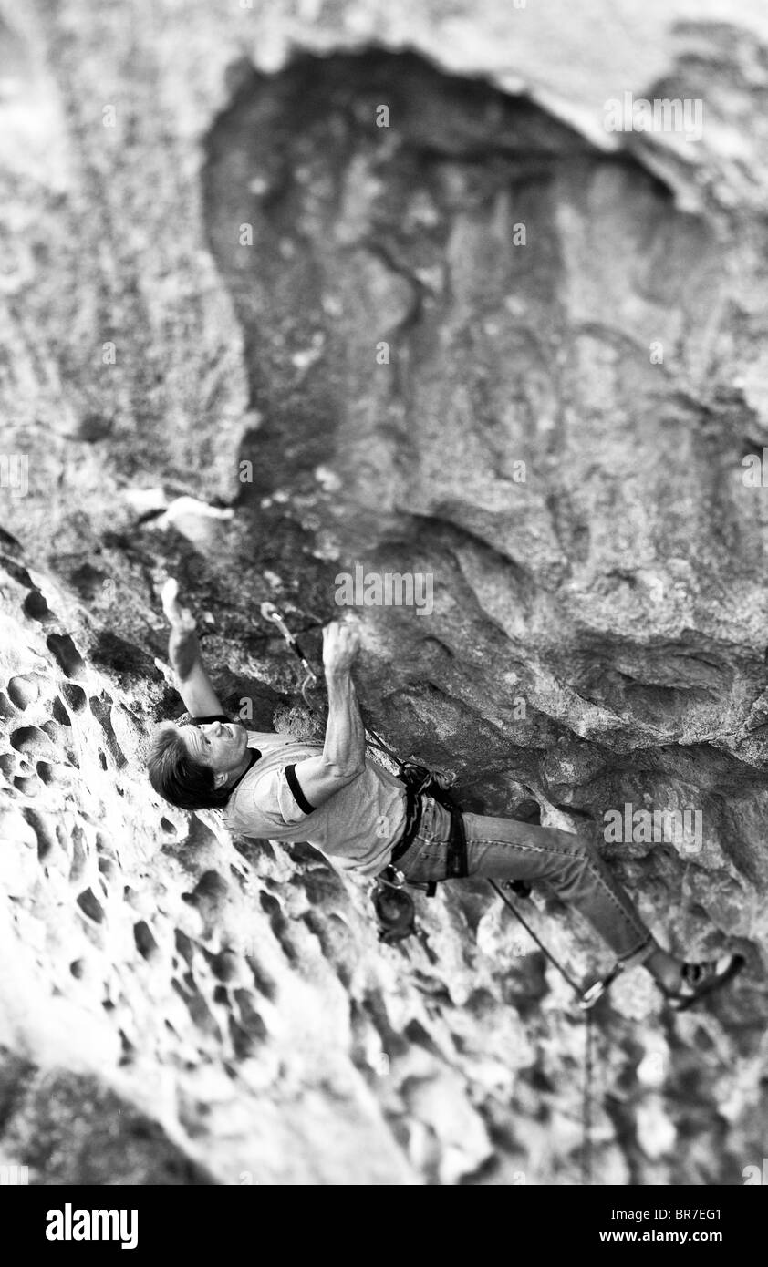 Rock climber grips a crack on a  sheer cliff. Stock Photo