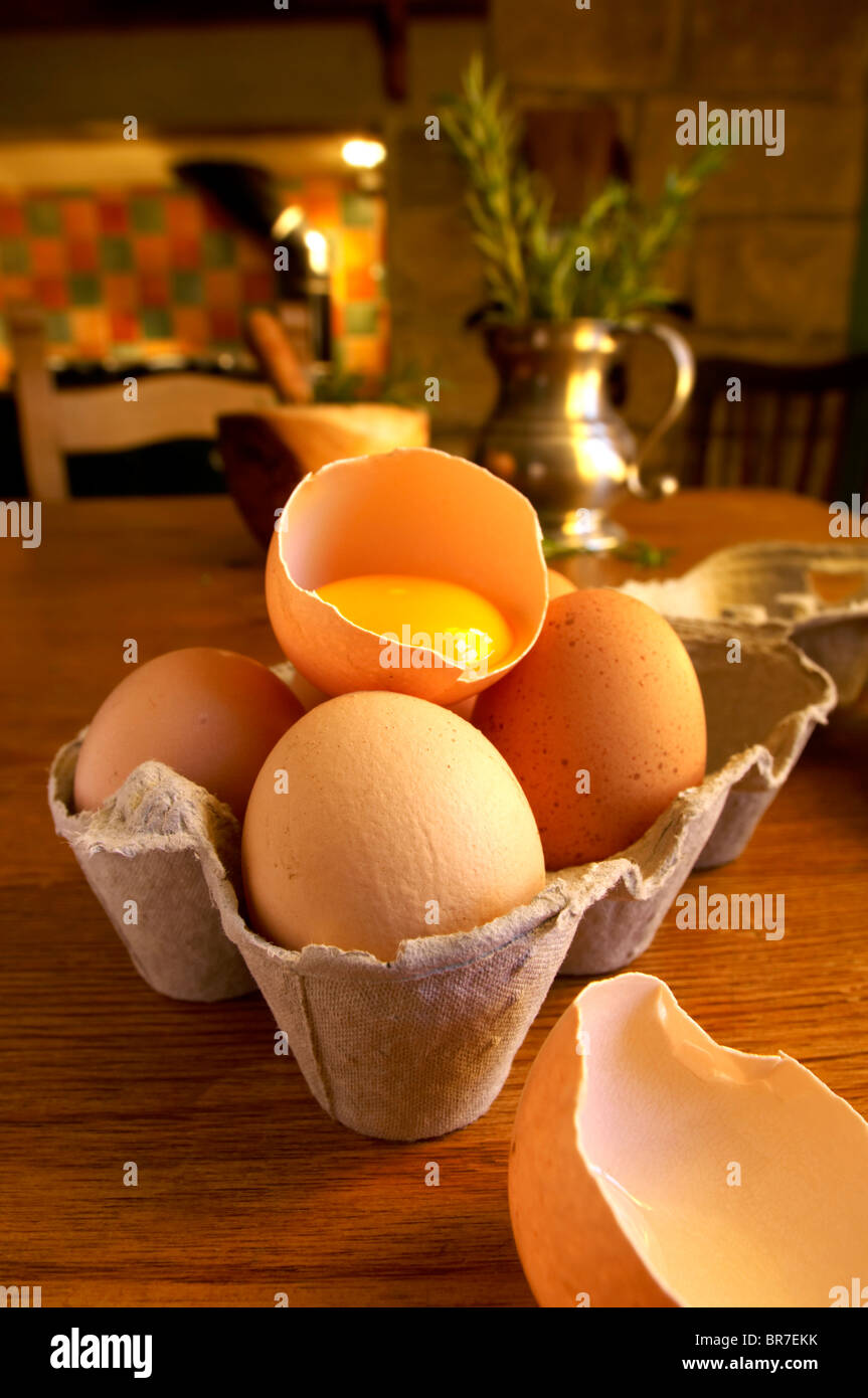 Free range eggs, one cracked with a yoke, in a coutry kitchen setting