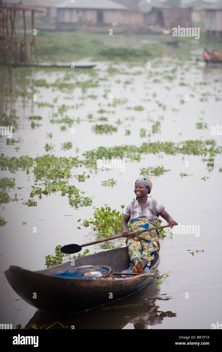 Young woman canoes through the village of Ganvie Stock Photo