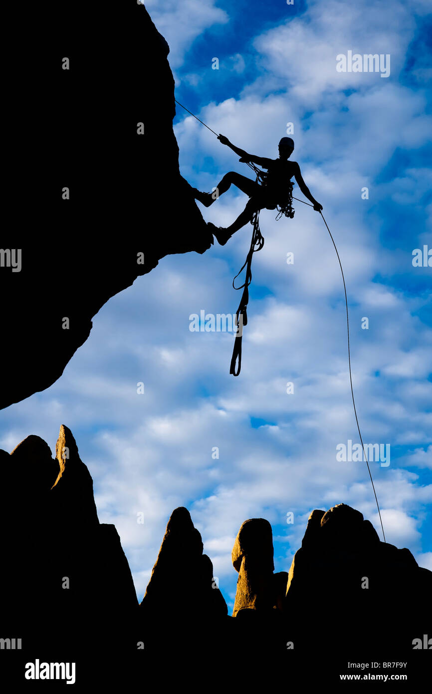 Rock climbers clings to the edge of a sheer cliff. Stock Photo