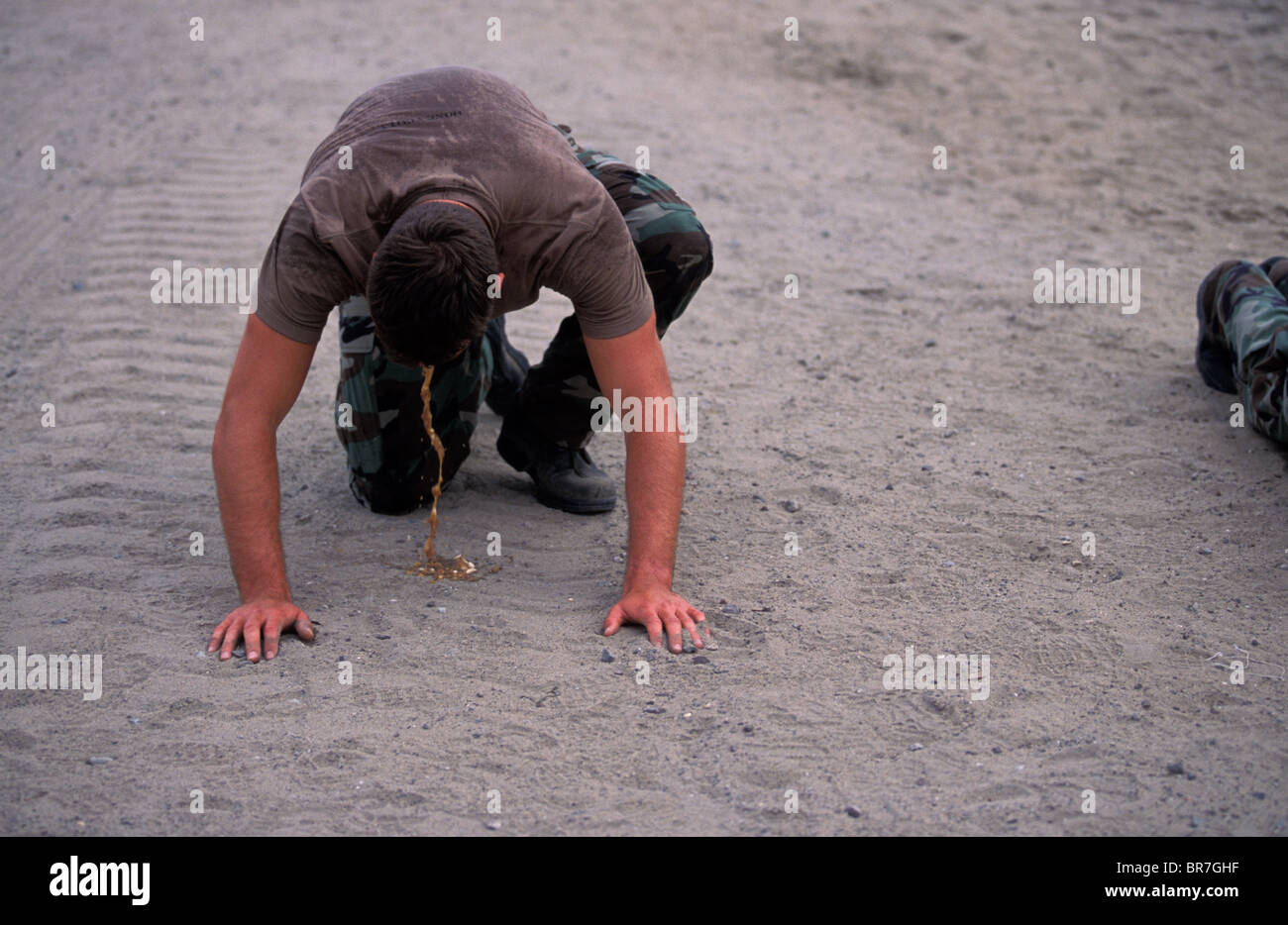 Man throwing up after doing push ups on the beach in San Diego