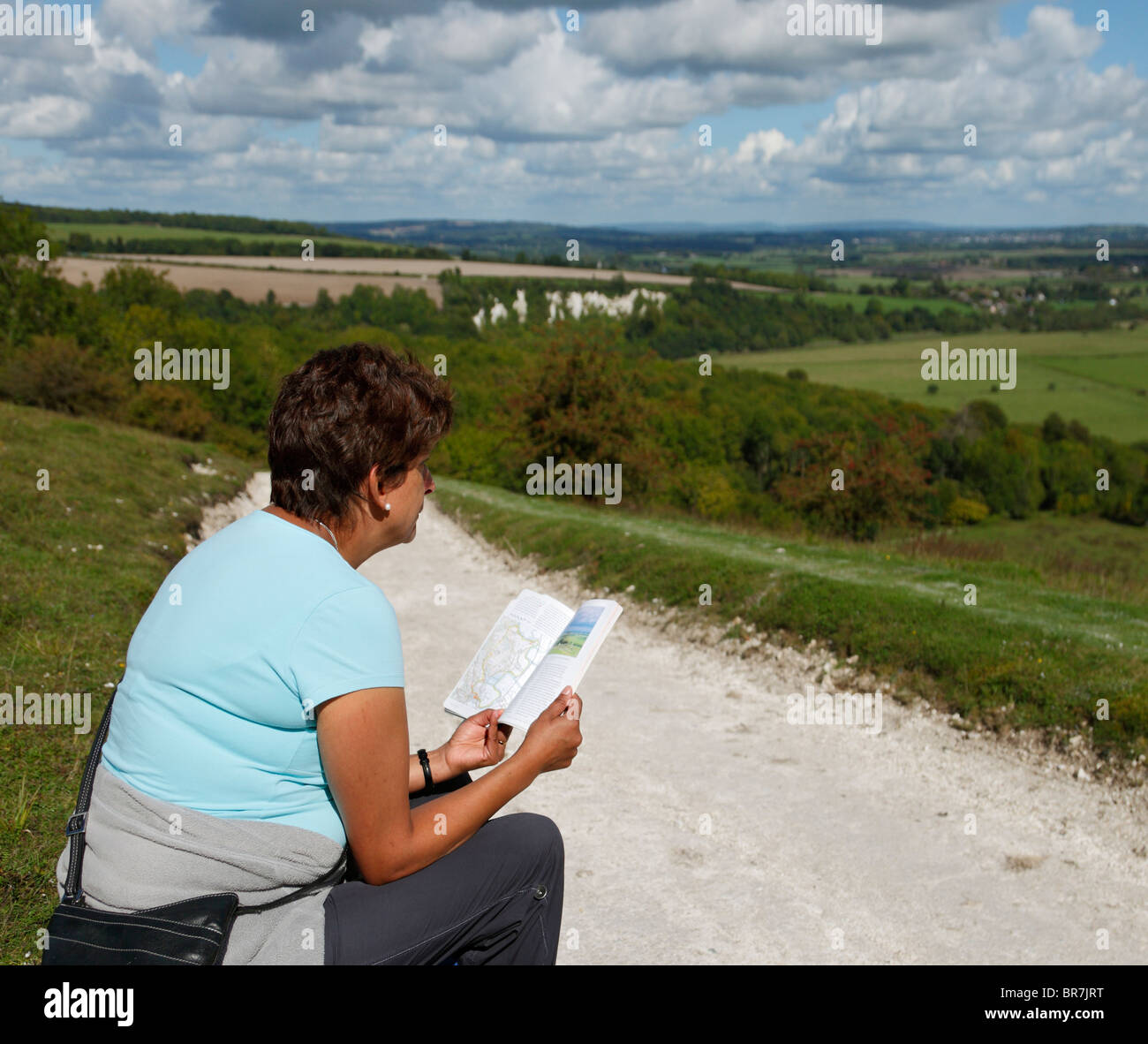 Woman reading a walking guide map on the South Downs. Stock Photo
