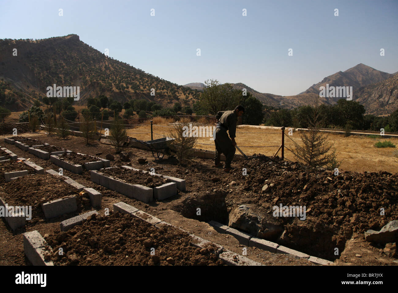 A HPG Kurdish fighter digging up a grave in Mehmet Karasungur Cemetery which is burial site for fallen Kurdish fighters of the People's Defense Forces HPG the military wing of the Kurdistan Workers' Party PKK located in the Qandil Mountains a mountainous area of Iraqi Kurdistan near the Iraq Iran border Stock Photo