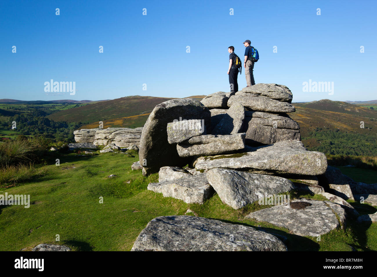 Two hikers on top of Combestone Tor, Dartmoor Stock Photo