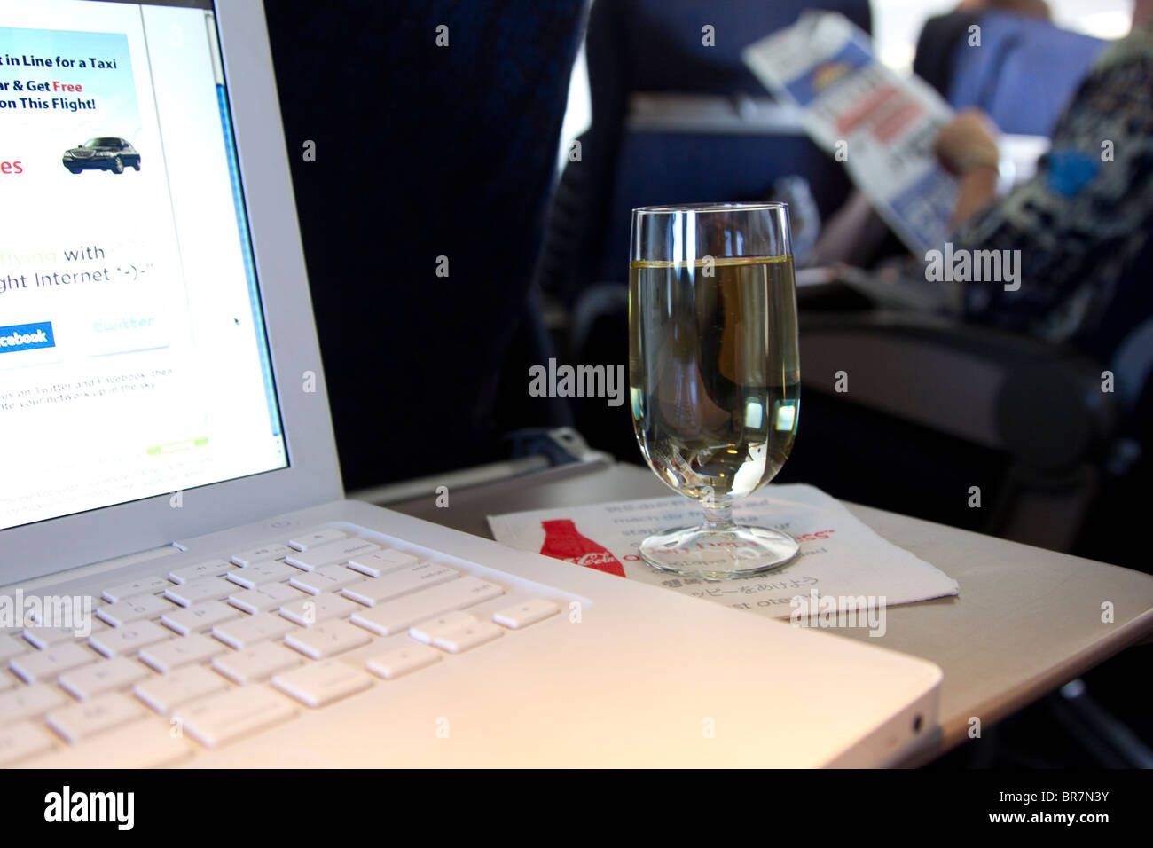 Glass of wine and laptop on tray table on first class airplane flight ...