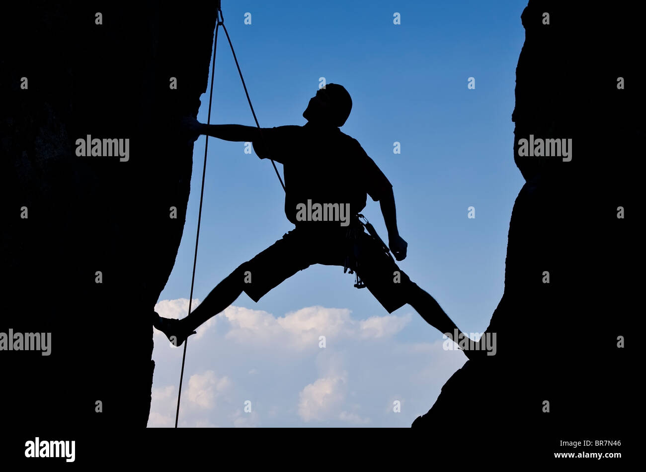 Rock climbers clings to the edge of a sheer cliff. Stock Photo