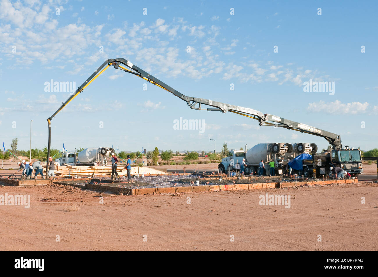 A crew of workers pour concrete from a boom truck for the floor of a new house in Arizona. Stock Photo