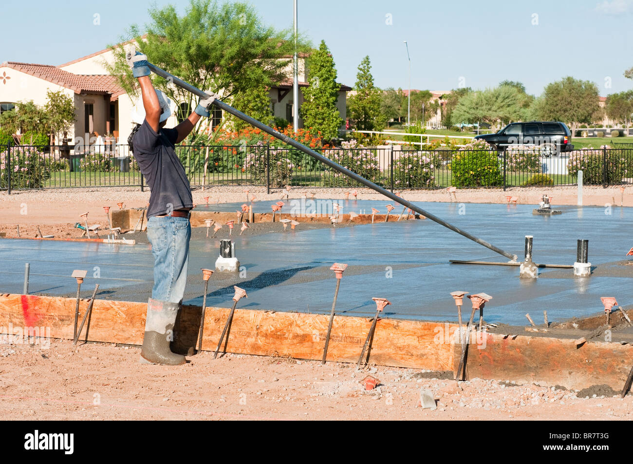 A construction worker finishes a newly poured concrete slab with a