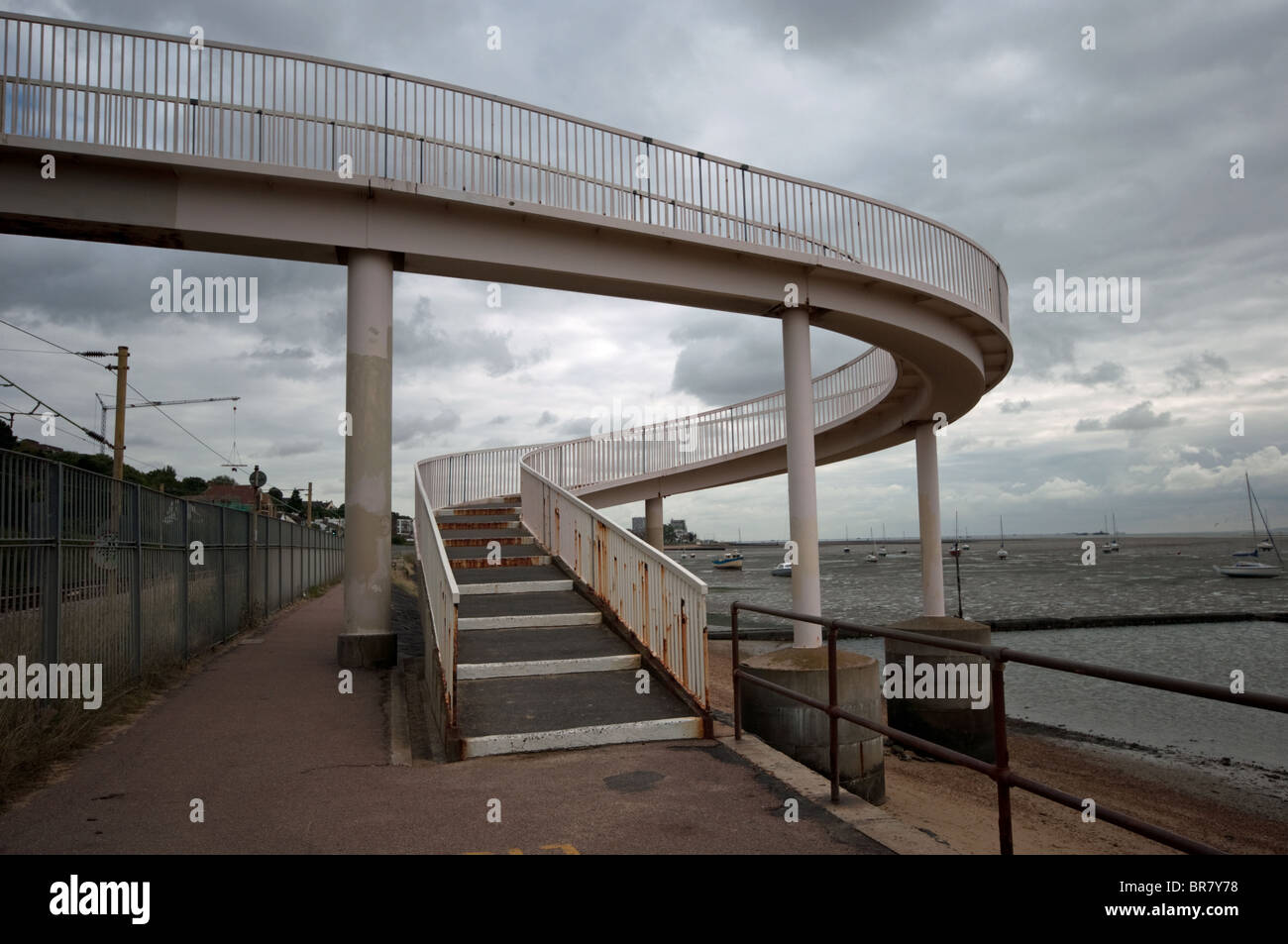 Curved ramp to distressed pedestrian bridge over railway track by the