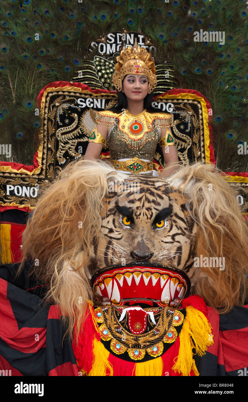 A Female Reog Dancer is sitting on a Sisingaan, while waiting to perform. Reog is Indonesian traditional dance from Ponorogo, East Java, Indonesia. Stock Photo