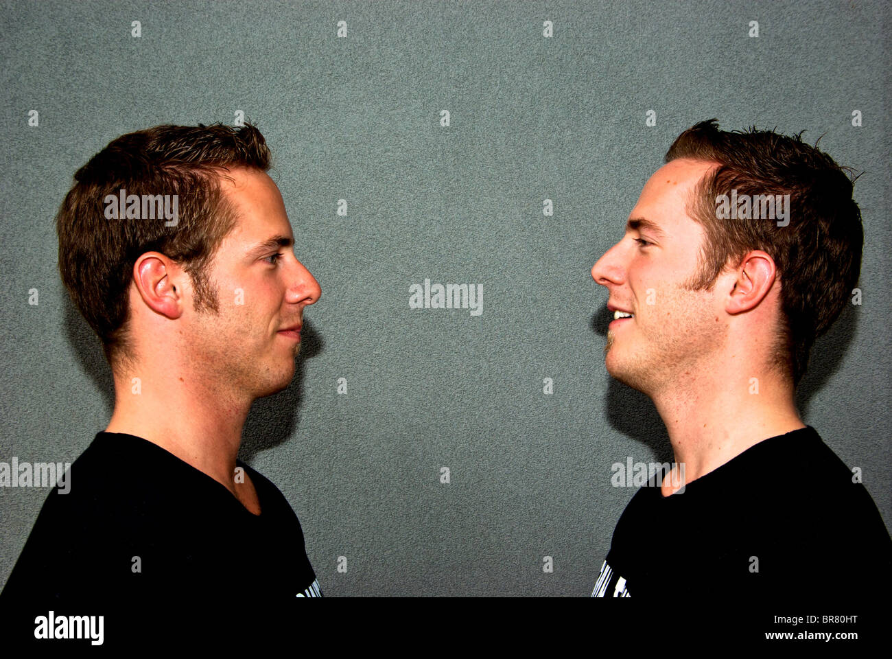 Identical young adult twin brothers dressed alike in same black T