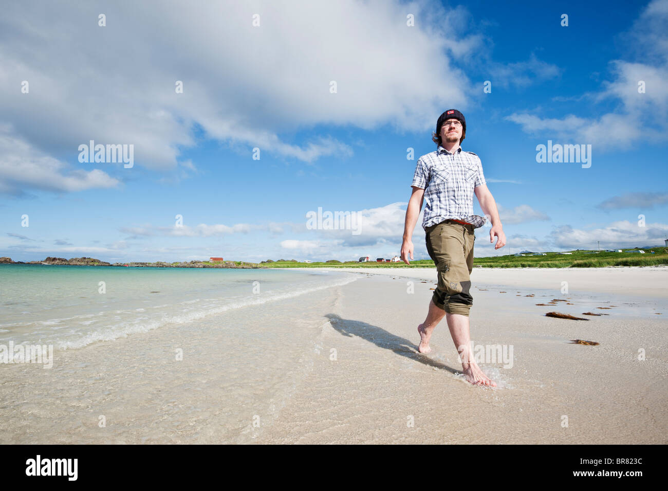 Person walks along scenic white sand beach, Gimsøya, Lofoten islands, Norway Stock Photo