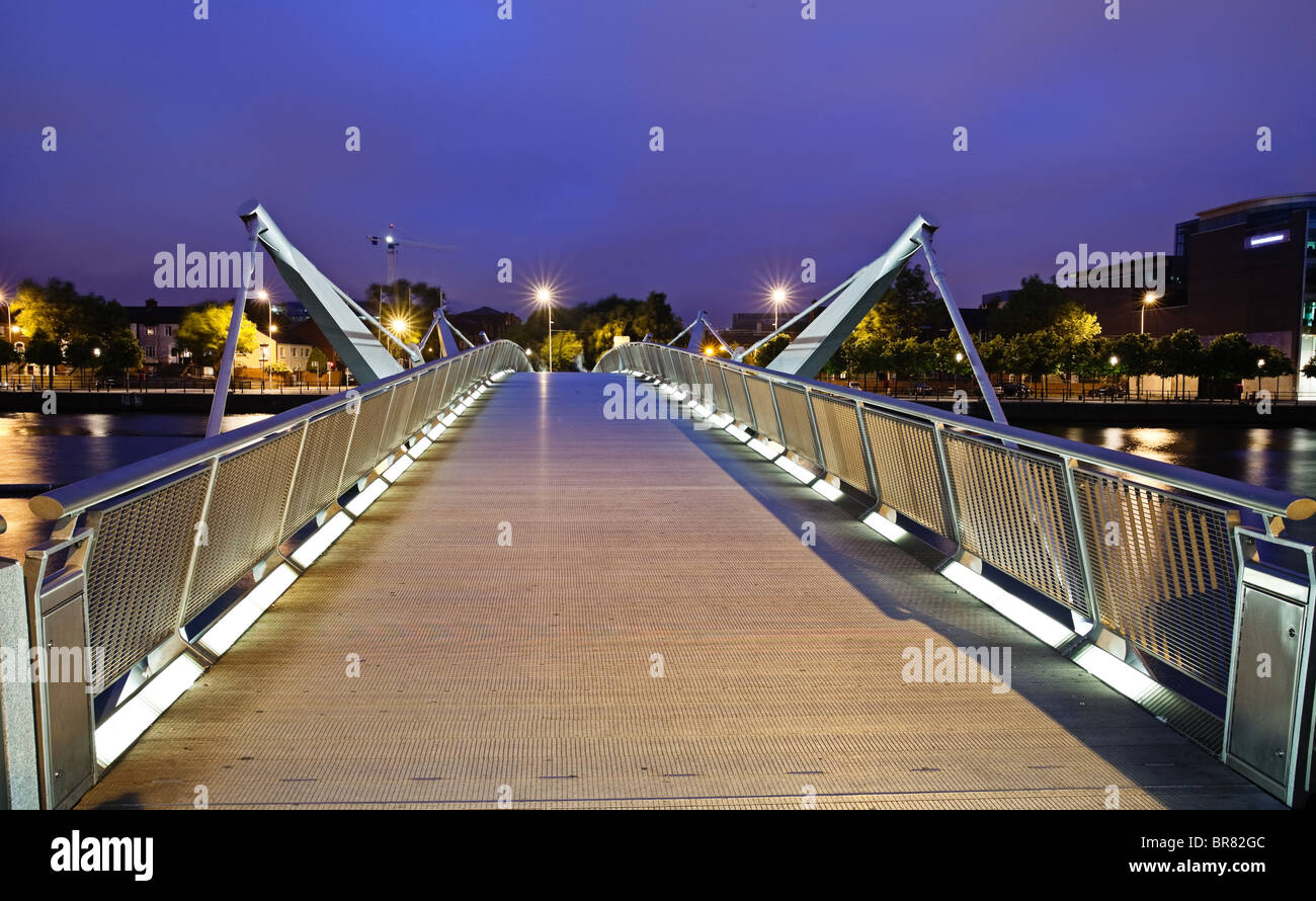 Illuminated pedestrian bridge across river Liffey in Dublin photographed in twilight Stock Photo