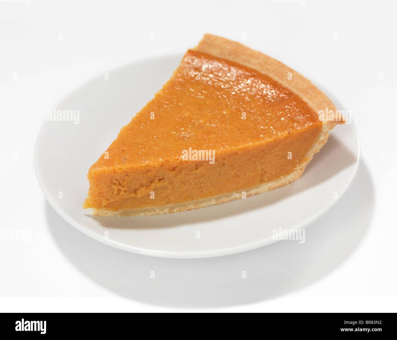 Piece of a pumpkin pie on a saucer isolated on white background Stock Photo