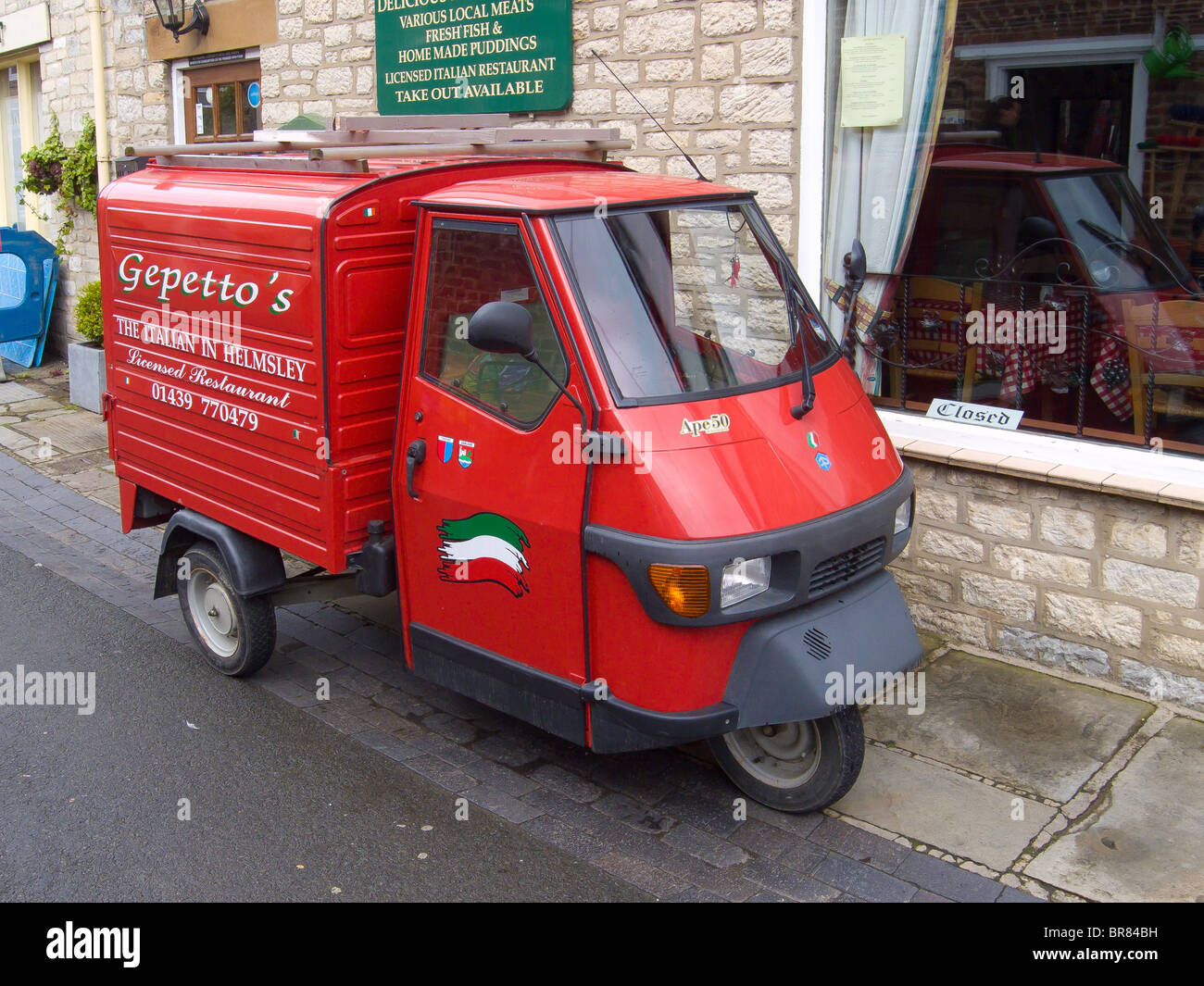 Bright red Piaggio Ape 50 van used by an Italian restaurant in Helmsley North Yorkshire England UK Stock Photo