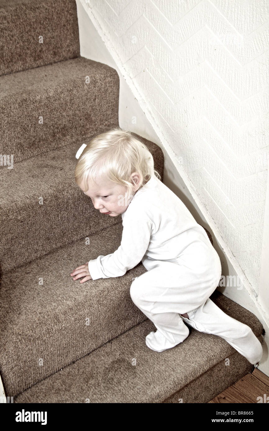 toddler climbing up the stairs to bed Stock Photo