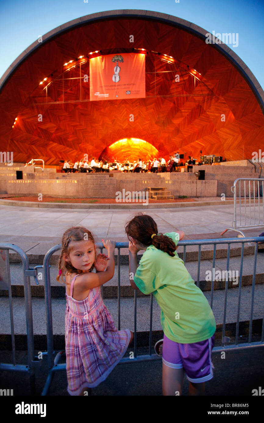 Two children watch a performance of the Boston Landmarks Orchestra at the Hatch Shell in Boston Massachusetts Stock Photo